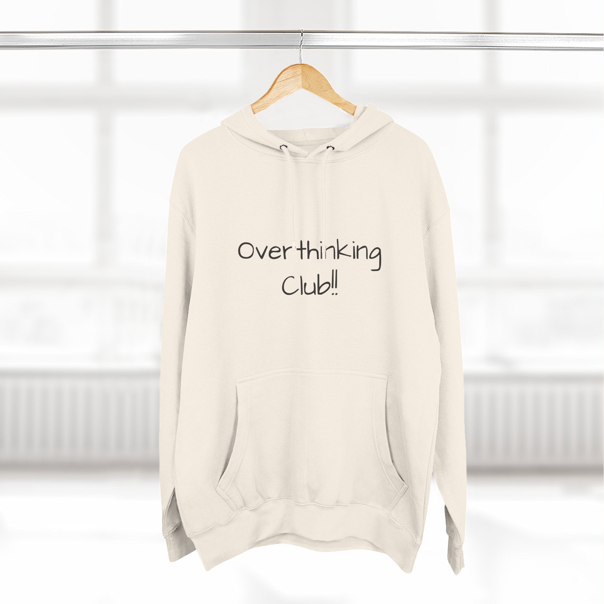 Beige hoodie with 'Over thinking Club!' text on a hanger against a white background