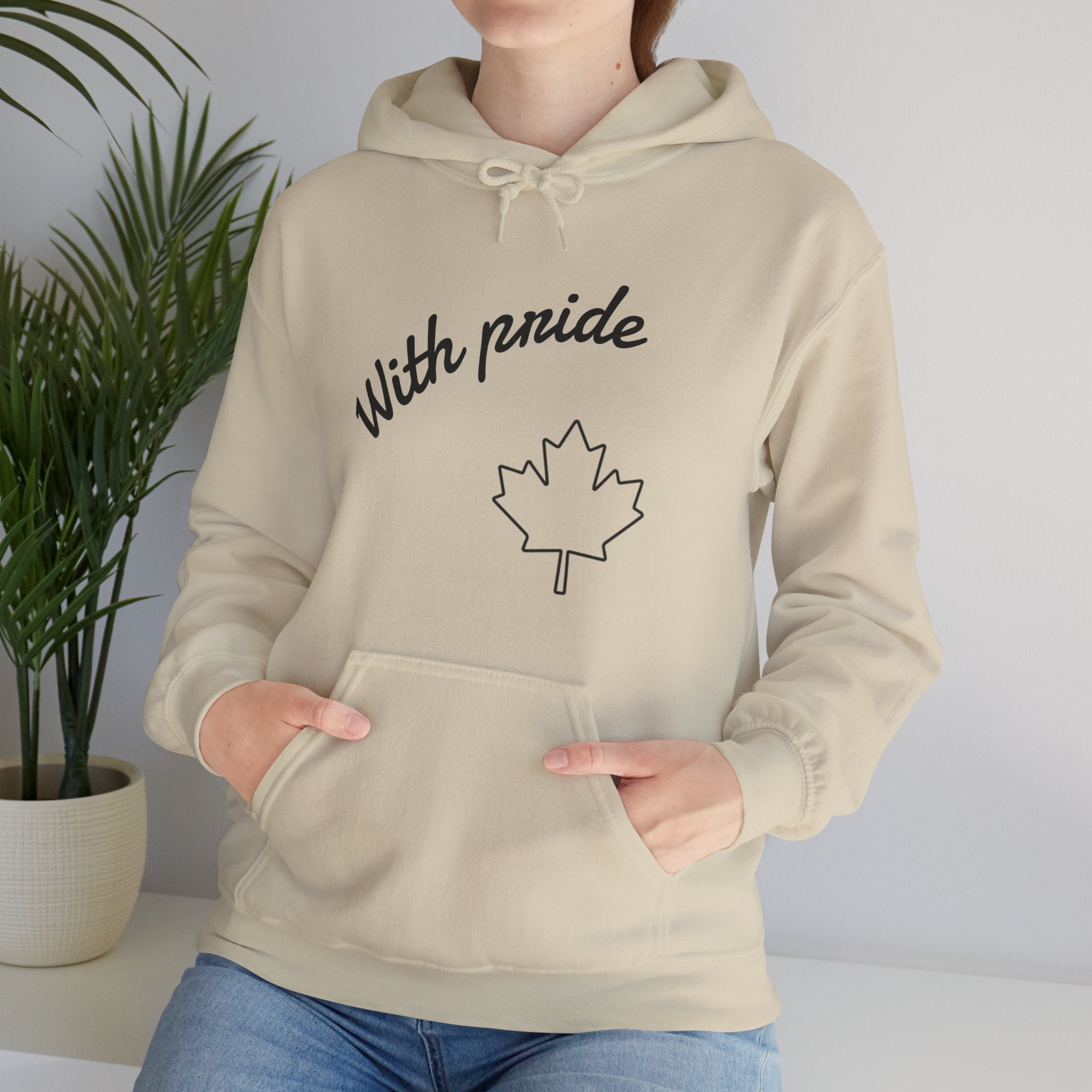 Person wearing a beige hoodie with 'With pride' and a maple leaf design, standing against a plain background.