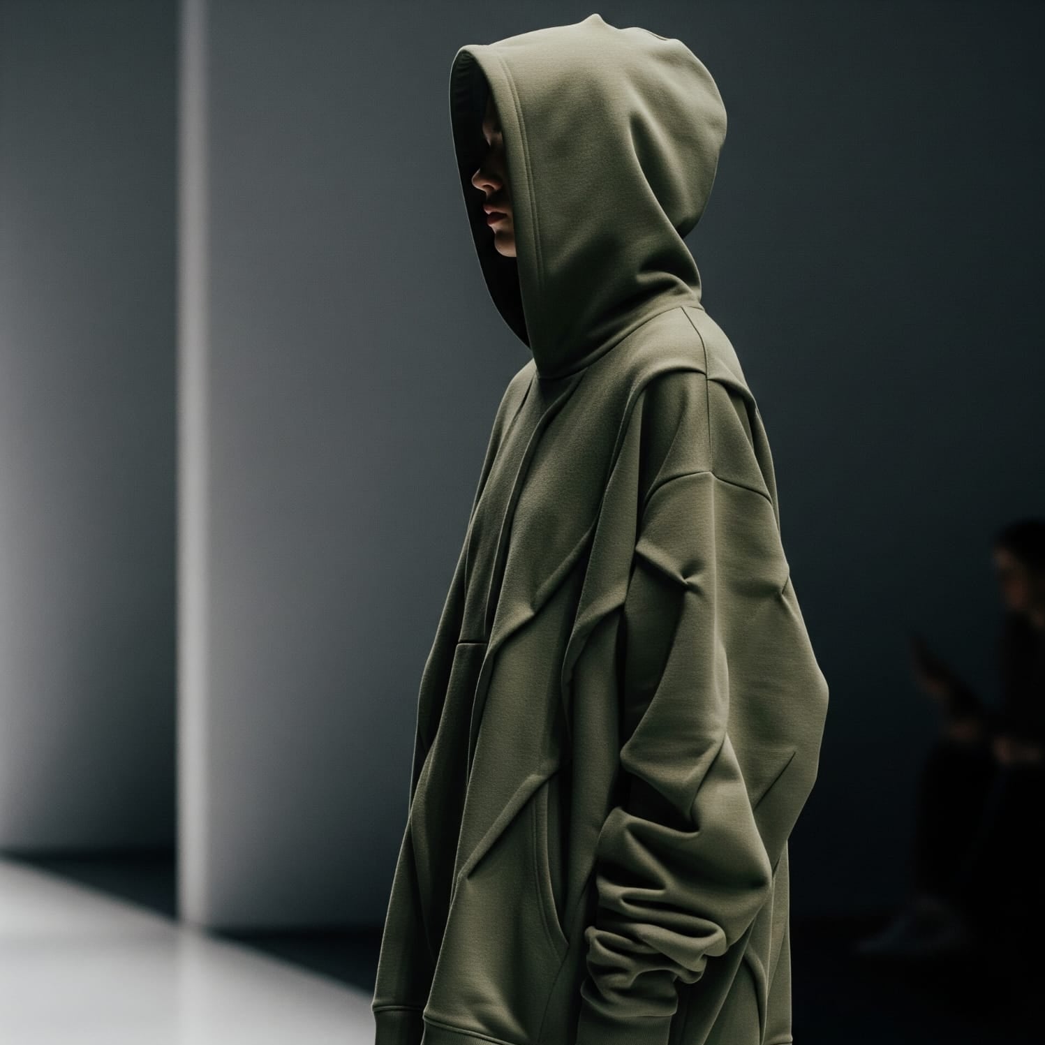 Person wearing a green hoodie in a dark setting